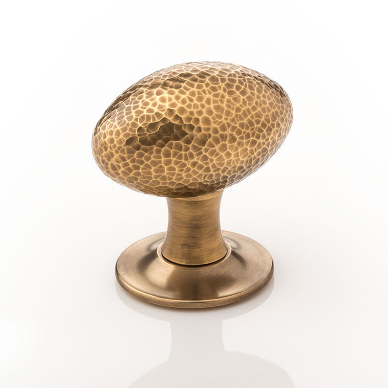 Intricately hammered solid brass oval door knob with tapered rose