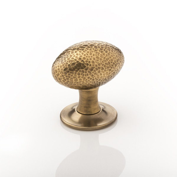 Intricately hammered solid brass oval door knob with tapered rose